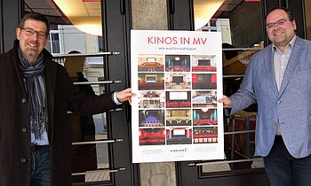 Geschäftsführer Volker Kufahl und Projektleiter "Strategische Kinoplanung", Fabian Liebenow, von der FILMLAND MV gGmbH präsentieren das Plakat.